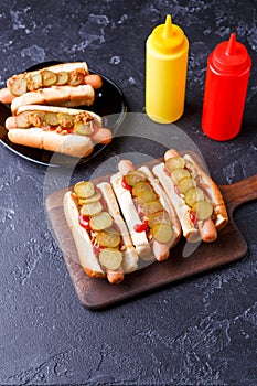 Photo on top of hotdogs on plate and board with ketchup and mustard