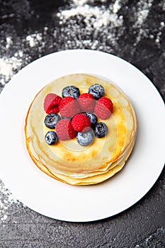 Photo from top of plate with pancakes, blueberries, raspberries