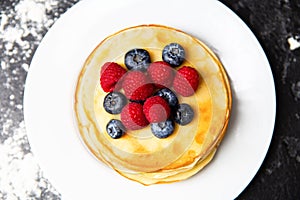 Photo from top of plate with pancakes, blueberries, raspberries