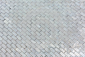 Photo on top of the road paved with sidewalk tiles. Blank background with, masonry texture of light gray bricks.