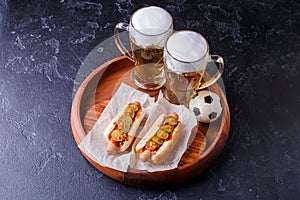 Photo on top of two glasses of beer and hot dogs on wooden tray with football