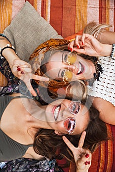 Photo from top of two joyful hippie girls, smiling and lying on