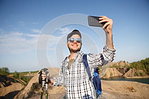 Photo of tourist man with walking sticks photographing himself on mountain hill
