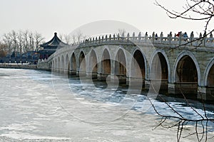 A traditional Chinese style arch bridge on the frozen lake in winter, Beijing, China