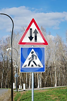Photo of triangle traffic sign for two way.Two-way traffic sign with red triangle and a pedestrian crossing sign