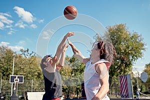 Photo of two athletes playing basketball on summer day