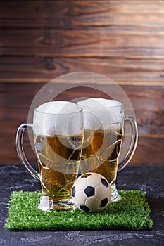 Photo of two beer mugs, green grass with soccer ball photo