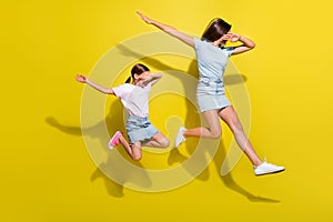 Photo of two cheerful energetic girls sisters jump dancing in dabber style isolated over bright color background