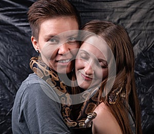 Photo of two happy women with python on neck