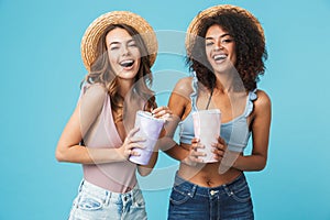 Photo of two joyful multiethnic women 20s wearing straw hats and