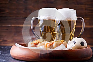 Photo of two mugs of beer and hot dogs on wooden tray with football