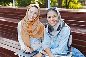 Photo of two muslim women wearing headscarfs smiling at camera