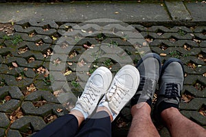 Photo of two pairs of feet in different colored shoes