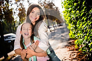 Photo of two peaceful carefree sisters cuddle have good mood free time walk sunny weather park outdoors