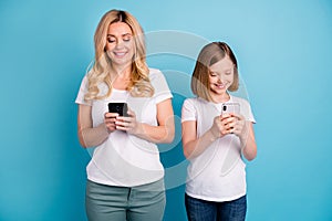 Photo of two people beautiful mom lady little daughter blonds spend time together hold telephones hands writing new post