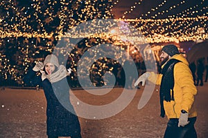 Photo of two people guy lady playing lights night park x-mas night throwing snowballs having fun free time wear warm