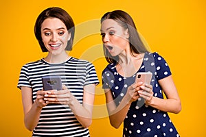 Photo of two pretty ladies holding telephones reading good news not believe luck wear summer casual trendy t-shirts