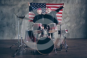 Photo of two retired people rock group photographing for american magazine hold usa flag patriots stand near instruments