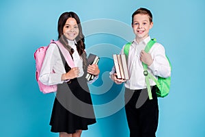 Photo of two small girl boy schoolchildren brother sister classmates hold books walk library study year finishing wear