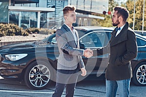 Photo of two smart elegant men, which have a deal about car.