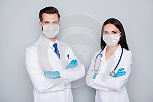 Photo of two specialists doc guy lady virology clinic experienced doctors arms folded wear protective flu facial masks