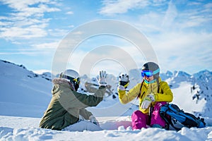 Photo of two tourists doing handshake sitting on snow resort .