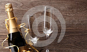 Photo of two wineglasses, bottle of champagne, gold ribbons