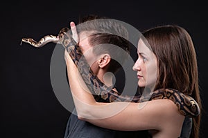 Photo of two women with python on closed eyes in profile