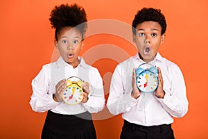 Photo of two young black kids amazed shock hold timer late missed lesson isolated over orange color background