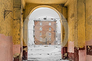 Photo of a typical five-story brick house framed in the arch of an old house