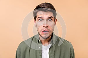 Photo of unhappy upset young man astonished stupor stare isolated on pastel beige color background