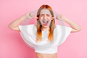 Photo of unhappy upset young woman cover fingers ears bad mood scream avoid isolated on pink color background