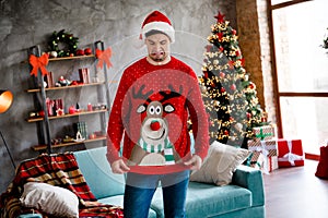 Photo of unsatisfied unpleased young person look reindeer print festive sweater living room house inside