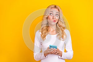 Photo of unsure milennial blond lady hold telephone look promotion wear trend cloth isolated on yellow color background