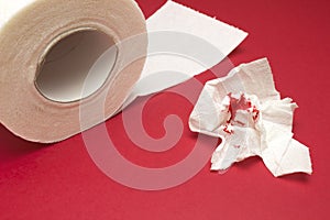 A photo of used bloody toilet paper and a tiolet paper roll. Blood drops and traces. Hemorrhoids, constipation treatment health pr