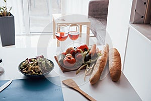 Photo of vegetables, salad and two glasses with red wine at the table