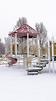 Photo Vertical Colorful playground for children at a park covered with snow at winter season