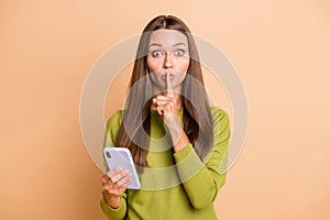 Photo of voiceless lady hold telephone finger cover lips wear green pullover isolated beige color background