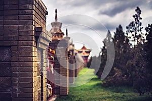 Photo of wall with prayer flags near eastern buddhist temple under clouds.