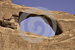 Wanning crescent moon caught in the middle of Skyline Arch photo