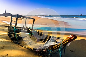 Seascape with A Broken Old Fishing Boat on Sandy Beach in Morning Sunshine