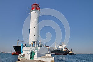 Modern container ship sailing near the old Odessa lighthouse