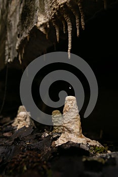 Photo of water droplet falling onto stalagmite covered with limestone