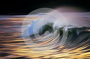 Photo of a wave breaking at sunset