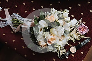 Photo of wedding accessories. Luxurious bouquet of the groom. Gold rings on a stand with flowers, a black classic watch on a