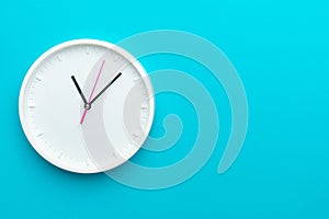 Photo of white wall clock over turquoise blue background with copy space