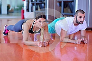 Photo of a woman doing pushups in a gym withe her personal trainer