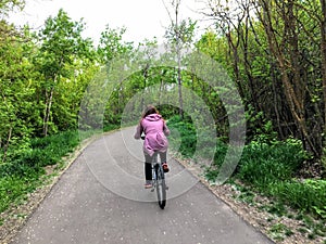 A photo of a woman enjoying a nice bike ride through the forest on a beautiful spring evening in the river valley