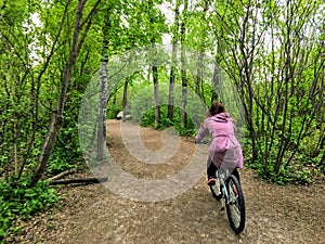 A photo of a woman enjoying a nice bike ride through the forest on a beautiful spring evening in the river valley