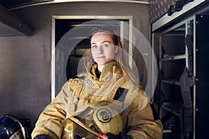 Photo of woman firefighter with helmet in her hands standing in fire truck